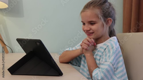 child girl watches videos and communicates on social media on a tablet at home. Generation Z. gadget addiction. 