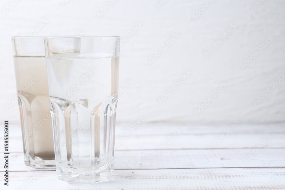 Obraz premium Glasses with clean and dirty water on white wooden table. Space for text