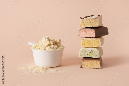 Different whey protein bars with various coatings and sprinkles scoop of protein powder on pink background. Healthy fitness snacks.