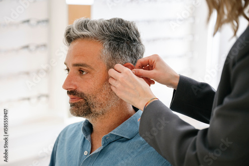 A man having a hearing aid fitted by a professional in a shop