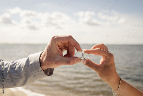 Brautpaar zeigt ihre Eheringe bei einer Strandhochzeit