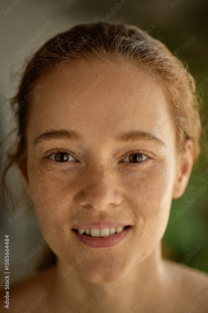 Obraz premium Close-up of cheerful young woman with glowing freckles and joyful expression. Concept of natural charm, radiant skin, wellness, personal identity, and skincare in advertising and media.