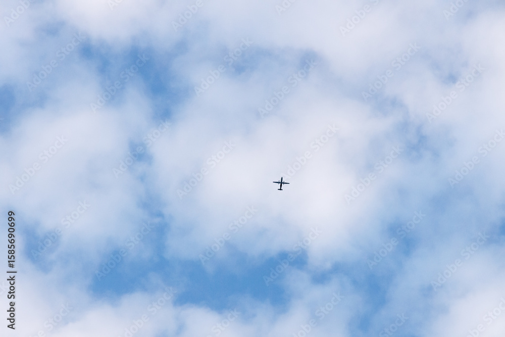 Airplane flying through the sky in far distance passing through the clouds Airplane flying through the sky in far distance passing through the clouds
