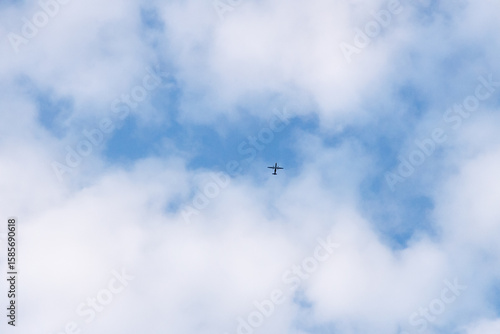 Fototapeta Naklejka Na Ścianę i Meble -  Airplane flying through the sky in far distance passing through the clouds