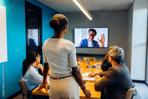 Fotografi Team meeting with virtual participant displayed on an office screen