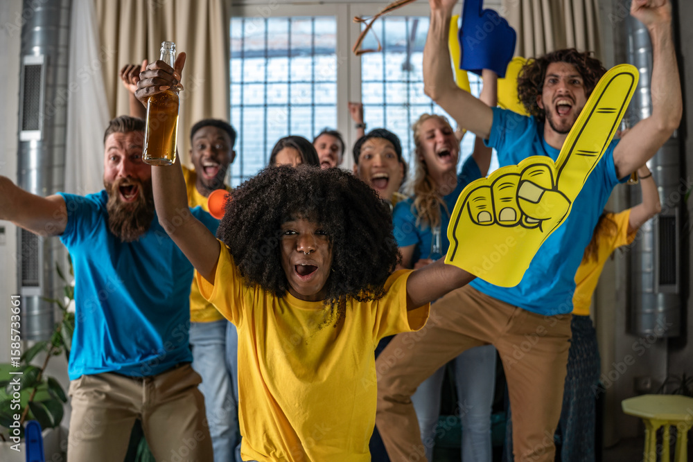 Fototapeta premium Diverse group of young fans celebrating a thrilling match win at home, with foam fingers, drinks, and pure energy. Joyful reactions and colorful expressions fill the room. Team spirit concept.