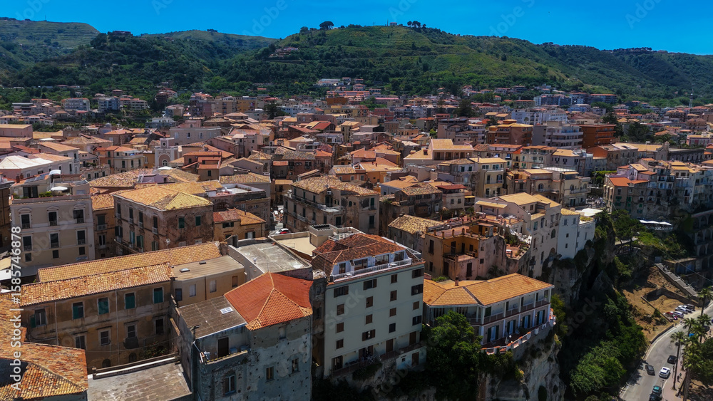 Fototapeta premium Aerial view of Tropea, a charming town perched on a cliff overlooking the Tyrrhenian Sea, showcasing its terracotta rooftops and the beautiful Calabrian landscape