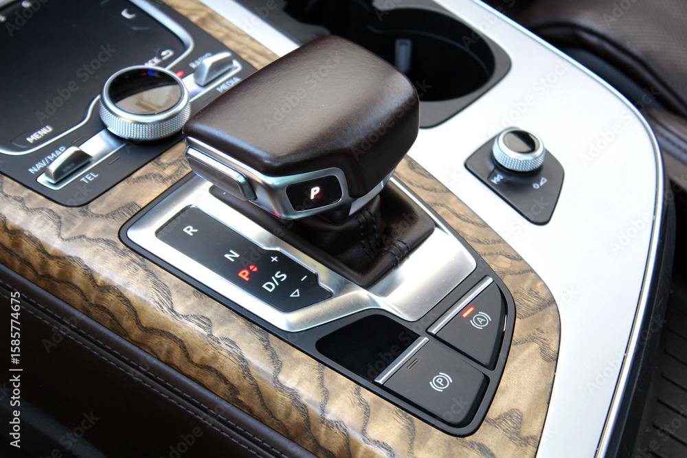 Fototapeta premium Automatic transmission gearshift stick. Lux car brown leather interior. Сar center console with cup holders. Close up of automatic gearbox lever, Closeup manual shift of modern car gear shifter.