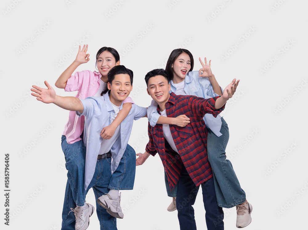 Fototapeta premium Cheerful friends give each other piggyback rides smiles and making OK gestures on white background