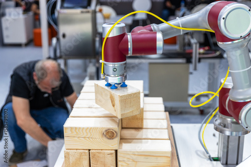 Fotografija Collaborative industrial robot arm operating alongside blurred human worker whil