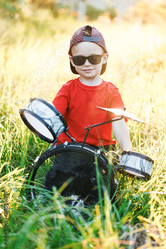 Happy Caucasian Child Beats the Toy Drum. Little Funny boy play drum. Guy Beats With Sticks on Toy Drums. Cheerful boy with drum sticks. Children Educational Concept.