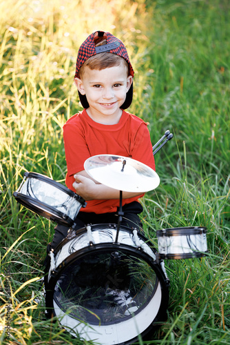 Smiling drummer boy crossed arms smiling at camera posing. Happy caucasian kid boy drummer. Guy playing on drum kit. Emotional portrait. Cheerful little boy playing drums.