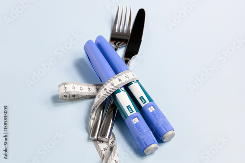 Concept of losing weight with Ozempic. Knife, fork and syringe wrapped in a measuring tape