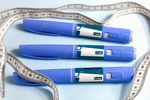 Three Ozempic syringe drug pen and measuring tape on blue