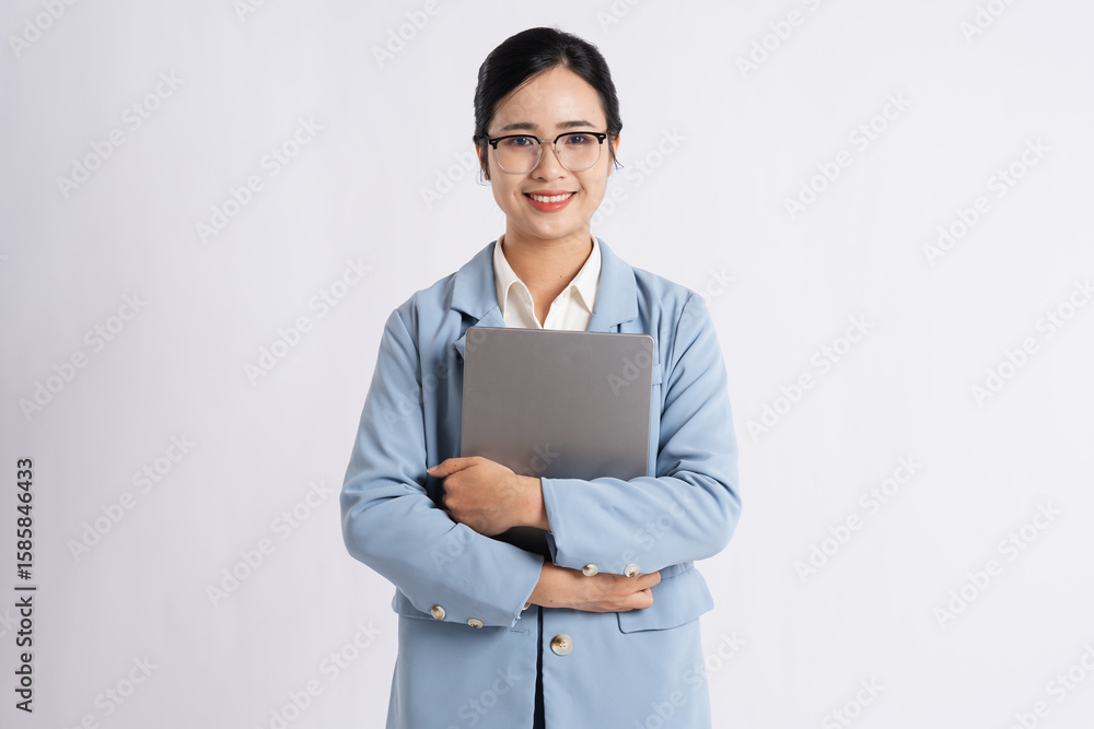 Smiling woman in business attire glasses holding laptop against a plain white backdrop Smiling woman in business attire glasses holding laptop against a plain white backdrop