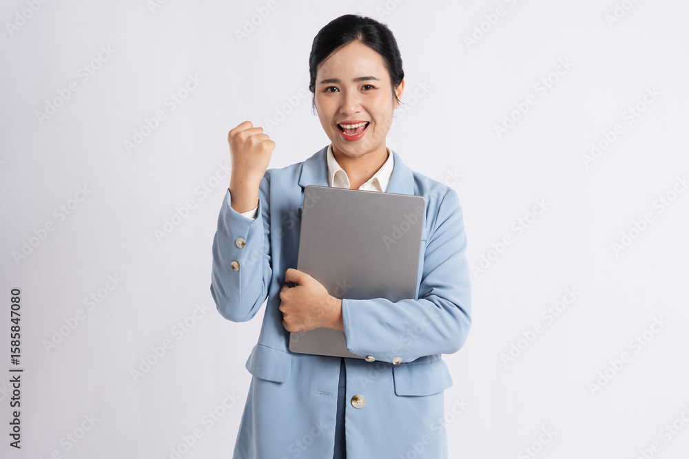Enthusiastic professional woman celebrating success with fist pump holding a closed laptop Enthusiastic professional woman celebrating success with fist pump holding a closed laptop