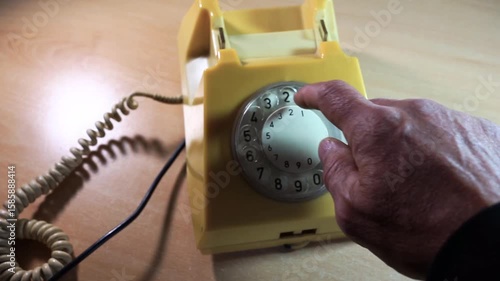 Caucasian man using an old analog telephone fabricated in the 1980's.