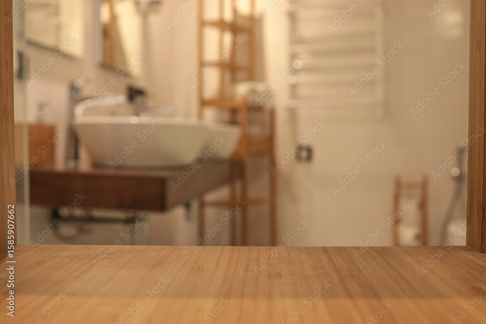 Fototapeta premium Wooden countertop in the foreground with a blurred view of a modern bathroom featuring two white vessel sinks, warm lighting, and wooden shelves in the background