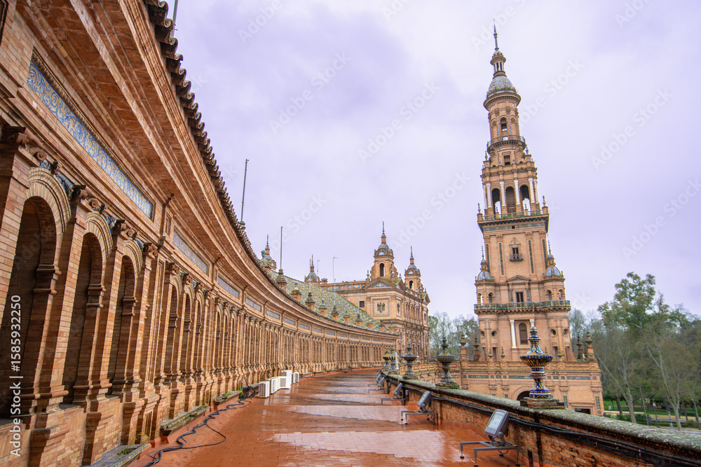 Sevilla Plaza de Espana in Spain shows a fountain under a rainy spring dusk sky, with ornate architecture and colorful tiles enhancing the serene scene. Sevilla Plaza de Espana in Spain shows a fountain under a rainy spring dusk sky, with ornate architecture and colorful tiles enhancing the serene scene.