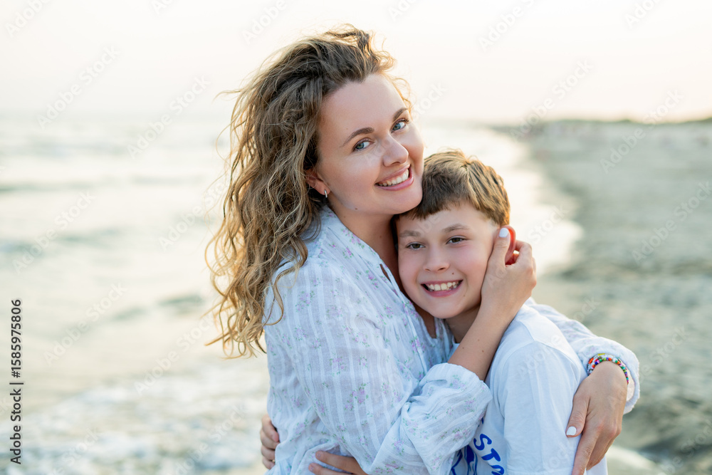 Young mother with little daughter near the sea. Beach with sand. Blue water. Young mother with little daughter near the sea. Beach with sand. Blue water.