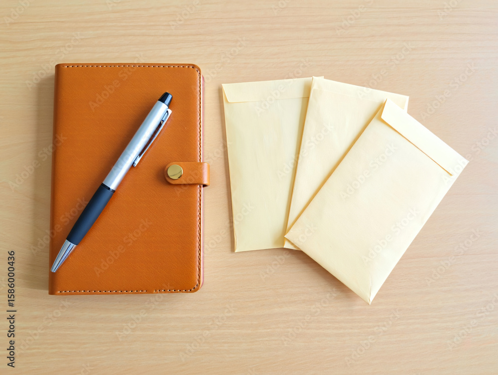 Stock photo of brown leather journal with pen and envelopes on wooden surface Stock photo of brown leather journal with pen and envelopes on wooden surface