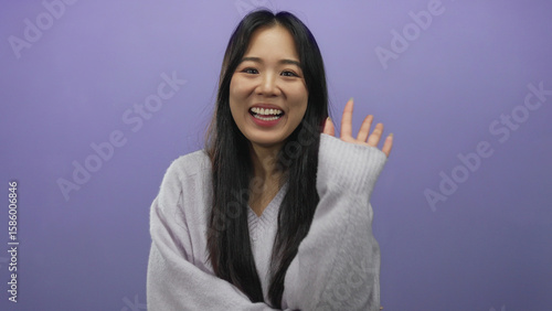 Obraz na plátně Young chinese woman smiling playfully over isolated purple background, conveying a sense of joy with long black hair and light gray sweater