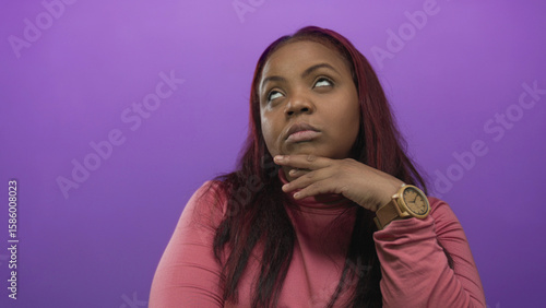 Fotografi Woman wearing wristwatch leaning on hand and hand on cheek against purple backdrop in studio; boredom