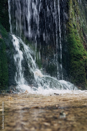 A waterfall with a green mossy rock wall