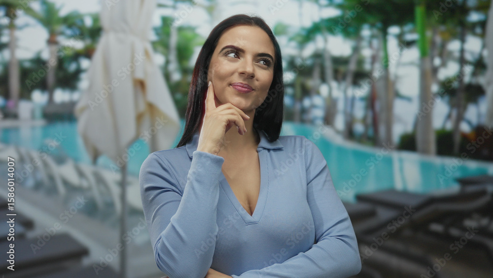 Woman pondering at a sunny hotel resort by the pool, surrounded by palm trees, exuding relaxation and vacation vibes while enjoying an outdoor leisure experience. Woman pondering at a sunny hotel resort by the pool, surrounded by palm trees, exuding relaxation and vacation vibes while enjoying an outdoor leisure experience.