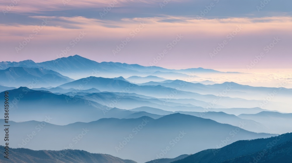 Obraz premium Scenic Misty Mountain Range during Sunrise with Soft Clouds and Fog in Nature.