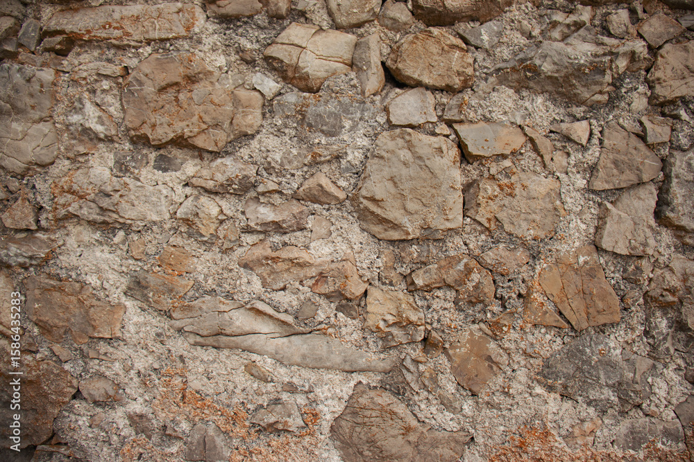 Naklejka premium Close-up of an old rustic stone wall with rough texture and natural earthy tones