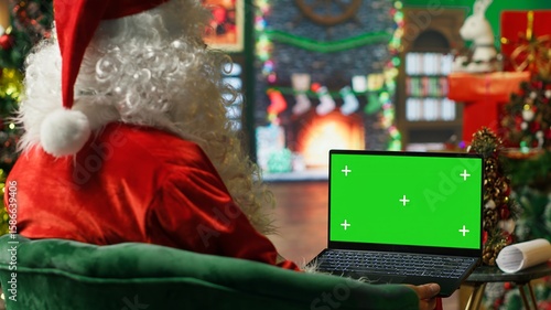 Fotografie Santa Claus making list of kids who has been naughty or nice on green screen laptop