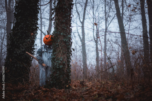 Murais de parede Pumpkin-headed scarecrow grips an axe in misty fall forest with chilling silence