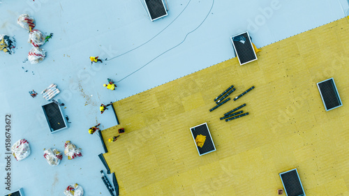 Top view of workers installing insulation layers on industrial flat roof