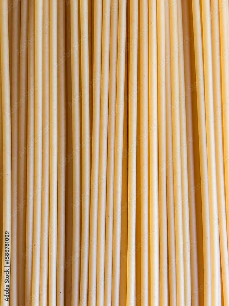 Fototapeta premium A Full Frame Background of Uncooked Bucatini Pasta Creating a Vertical Pattern