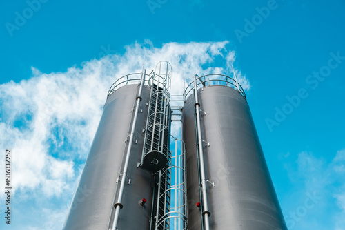 Industrial silos against blue sky with metal ladders and safety railings