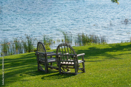 Two old chairs on a green meadow near the lake