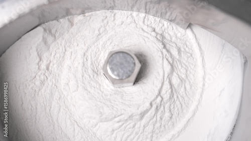 Close-up of a stainless steel pharmaceutical machine mixing white powder raw material for medicine or vitamin production in a cleanroom environment.