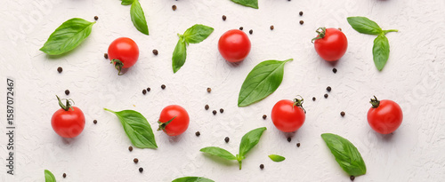 Composition with ripe cherry tomatoes, basil leaves and peppercorn on light background