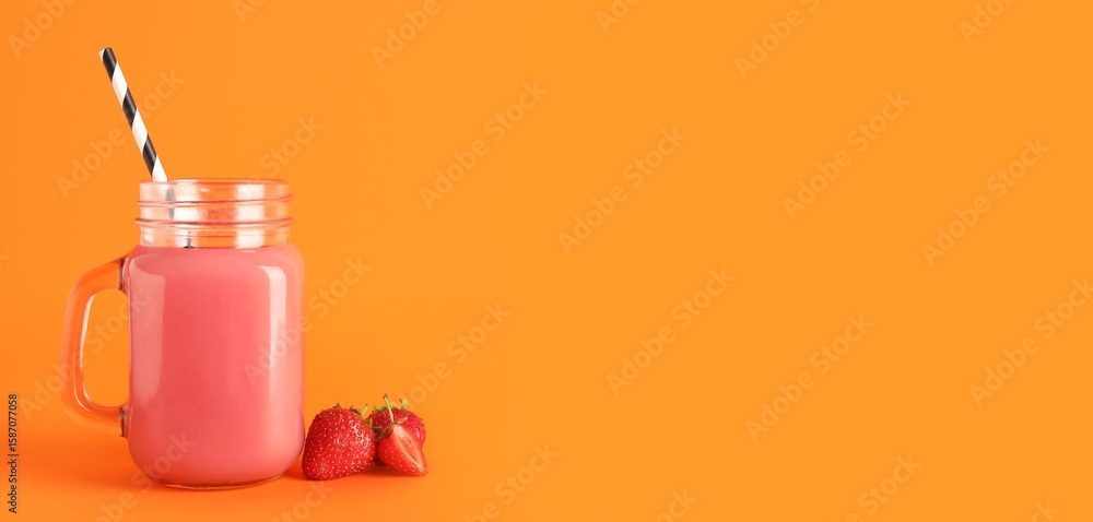 Obraz premium Mason jar of fresh strawberry juice on orange background with space for text
