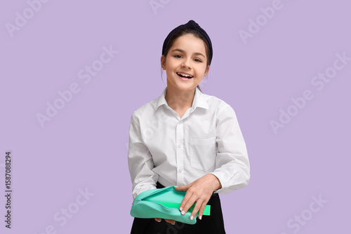 Little schoolgirl with pencil case on lilac background