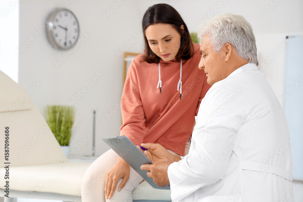 Obraz premium Senior doctor with clipboard talking to female patient in rehabilitation center