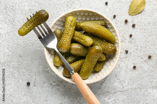 Foto Bowl with tasty pickled cucumbers and peppercorn on grey background
