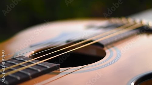 Close up shot of an acoustic guitar focusing on the strings and fretboard with blurred background