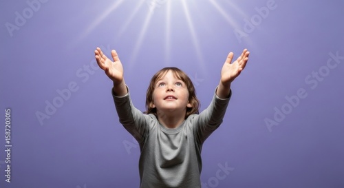 Photo of a joyful child with hands raised towards the light, looking up with a happy expression, symbolizing hope, faith, and spiritual connection against a purple background
