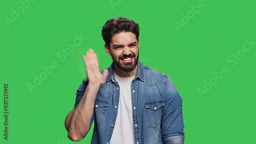 A young man with a beard and denim shirt expresses surprise against a green background, showcasing a casual and modern style