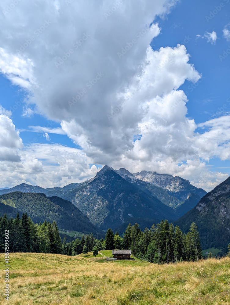 Obraz premium Mountain landscape in the Berchtesgaden National Park. View from the Eibl Chapel across a green meadow with a small, traditional wooden house over to Maria Kirchental at the foot of the Loferer Steinb