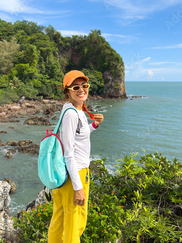 Female tourist standing on coastal path in tropical nature