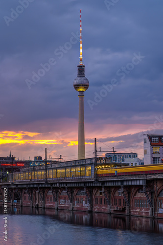 The famous Television Tower and the river Spree with a motion blurred train in Berlin at twilight