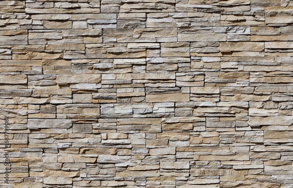 Obraz premium External wall coating made of striped stacked brown, gray and white rocks. Background and texture.